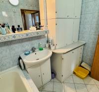 A bathroom in a 3-room apartment with a sink, cabinets, and a mirror.