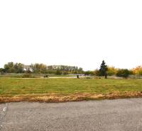 A grassy commercial plot on Nebojsa Street in Galanta with surrounding trees.