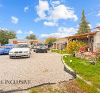 A family house in Dolné Saliby, with cars parked in front of the house and a well-maintained garden.