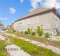 A family house in Dolné Saliby with a yard, plants, and parked cars.
