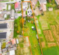 A top-down view of a family house and garden in Dolné Saliby, bordered by plots of land.