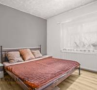 Cozy bedroom with a metal bed and wood-patterned flooring in a family house.