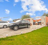 Parking in front of an unfinished family house in Dolné Saliby, trimmed lawn and vehicles.