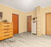 Interior of a family house with a wooden decor floor, a dresser, and two doors.