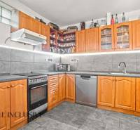 A kitchen in a family house with wooden decor, appliances, and gray tiles.