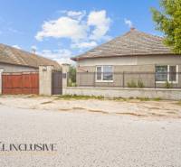 A family house in Dolné Saliby with a fence, a gate, and a tree nearby.
