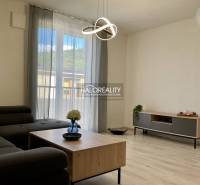 Living room in a three-room apartment with a sofa, table, and floor with a wooden decor.