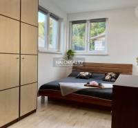 A bedroom in a 3-room apartment with a wood-patterned floor and large windows.