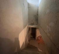 A staircase leading to the basement of a family house with exposed brickwork, without windows.