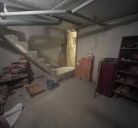 Basement in a family house with concrete stairs, shelves and pipes, found items.