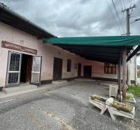 A family house in Plášťovce with a concrete courtyard and entrance door under a canopy.