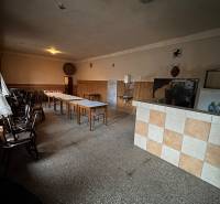 Room with long tables in a family house, with simple lighting and tiles on the wall.