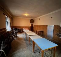 Dining room in a family house with wooden chairs and tables, pleasant lighting.