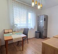 A bright kitchen with a dining table, refrigerator, and wooden decor flooring in a 3-room apartment.