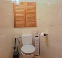 Bathroom with toilet in a 3-room apartment, light tiles, storage space with wooden doors.