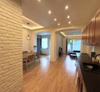 A family house with white brick walls, a wooden decor floor, and a dining table.