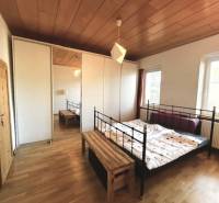 Bedroom with a metal bed and a wardrobe, floor with wooden decor in a family house.