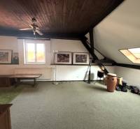 Attic room with carpeted floor, ceiling fan, and drums in a family house.