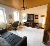 Living room with an office desk, sofa, and glass cabinet in a family house.