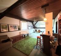 Attic living room of a family house with carpet and wooden ceiling.