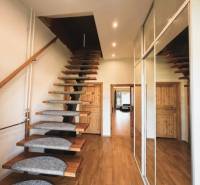 A staircase with a wooden decor floor and a mirrored wall in a family house.