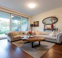 Living room in a three-room apartment with a wood-patterned floor and a large window.