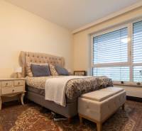 A bedroom with a comfortable bed, a nightstand, and a floor with a wooden decor in a 3-room apartment.