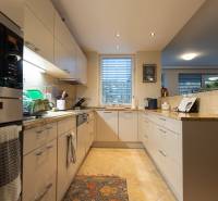 A kitchen in a 3-room apartment with white cabinets, tiles, and appliances.