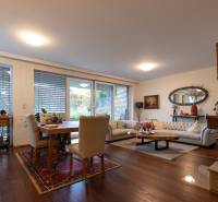 Living room in a three-room apartment with a wood-patterned floor and comfortable seating.