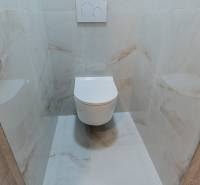A toilet with ceramic tiles in a 3-room apartment, white sanitary equipment.