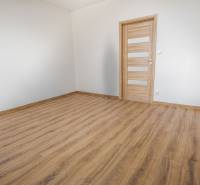 A room with white walls and a floor with a wooden decor in a 3-room apartment.