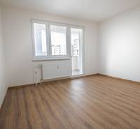 An empty room with a wooden floor and a French window in a 3-room apartment.