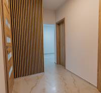 A hallway in a 3-room apartment with wooden doors and a decorative wall.