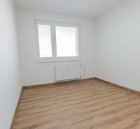 A room with white walls, a window, and a floor with a wood decor in a 3-room apartment.