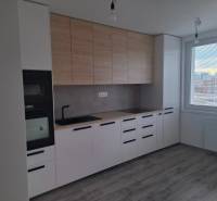 A kitchen in a 3-room apartment with a wooden decor floor and large windows.