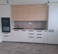A kitchen in a 3-room apartment with a wooden decor floor and built-in appliances.