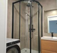 A bathroom with a shower, a washing machine, and a cabinet in a 3-room apartment.