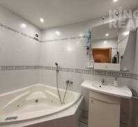 A bathroom with a bathtub and a mirror in a 3-room apartment. White tiles with a decor.