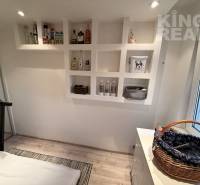 A room in a 3-room apartment with shelves, a treadmill, and a floor with a wooden decor.