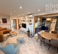 Living room with kitchen in a 3-room apartment, wooden decor flooring, comfortable seating.