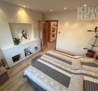 A bedroom in a 3-room apartment with a wood-patterned floor and wall decorations.