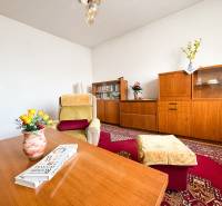 Living room in a family house with wooden furniture, a carpet, and a comfortable armchair.