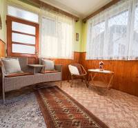 Interior of a family house with rattan furniture, floral curtains, and a carpet.