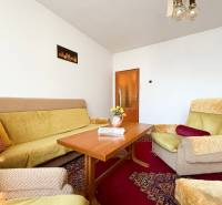 Living room in a family house with a sofa, armchair, table, and decorative cushions.
