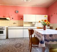 A kitchen in a family house with vintage furniture, a white kitchen unit, and colorful walls.