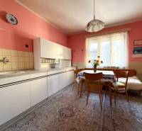 A kitchen in a family house with pink walls, retro furniture, and floral decorations.