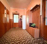 A hallway of a family house with carpet, wooden paneling, and built-in furniture.