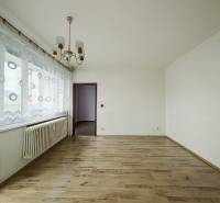 A room with a wooden floor decor and a chandelier in a three-room apartment.