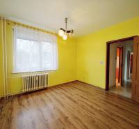Yellow walls and a wooden decor floor in a 3-room apartment with a radiator.
