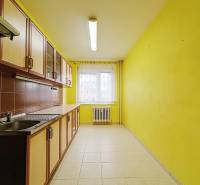 A kitchen in a 3-room apartment with yellow walls and brown tiles behind the counter.